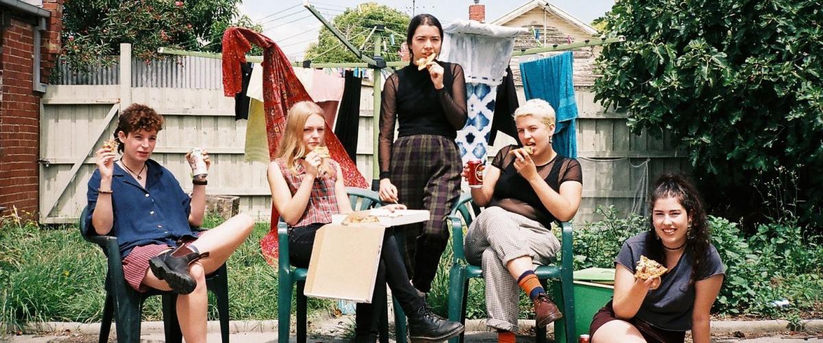 Melbourne five-piece Chelsea Bleach eating pizza in a backyard.