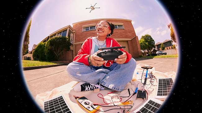 a girl sitting outside flying a drone